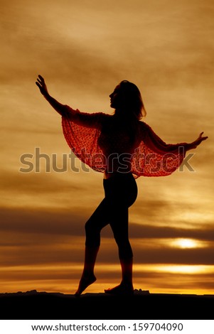 A silhouette of a woman with her arms out dancing.