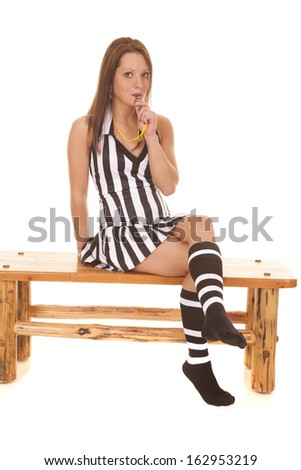 A woman referee is holding her whistle to her lips.