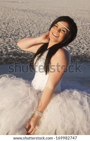 a close up of a woman in her formal dress smiling while standing on a frozen lake.