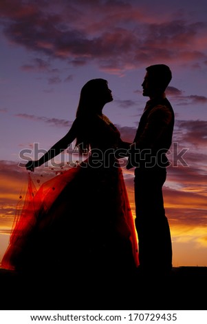 A silhouette of a western couple dancing in the light of the sunset.