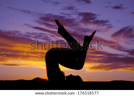 A silhouette of a woman on her shoulders with legs up in the sunset or sunrise.