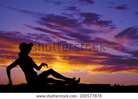 a silhouette of a woman sitting on the ground enjoying the outdoors.
