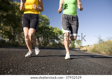 Two women legs while jogging outdoors.