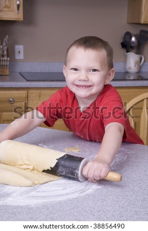 A boy using a rolling pin to roll out the dough.