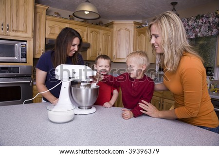 Two moms with their children helping them learn to bake.