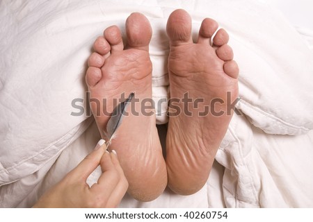 A woman with a feather in her hand tickling a man\'s feet.