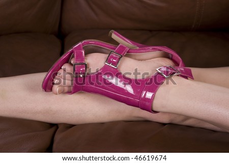 A woman laying on the couch with her pink high heel shoes on.