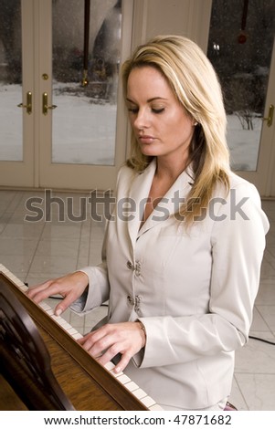 A woman playing the piano looking at her hands on the keys.