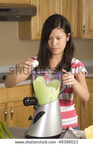A woman making a great smoothie placing an egg in her drink to make it healthy.