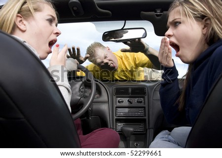Two teen girls in a car with shocked and scared expressions on their faces after hitting a man while they were being distracted by eachother.