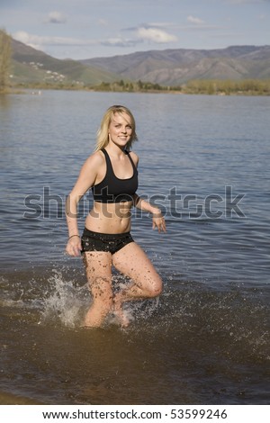 A woman running and cooling off in the water enjoying the refreshing feeling of the water.
