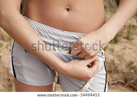 A woman is measuring her hips close up.