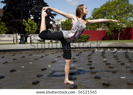 a woman doing her yoga stretch while in the park in some water to help her cool off.