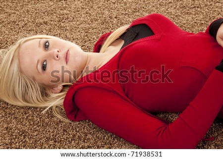 A woman in red is laying on her back on the carpet.