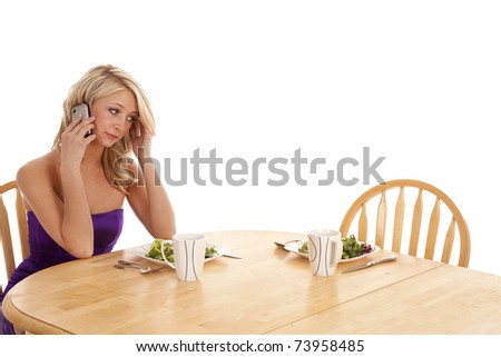 A woman with an unhappy expression on her face on her phone calling her date asking where he is at.  He is late for their dinner date.