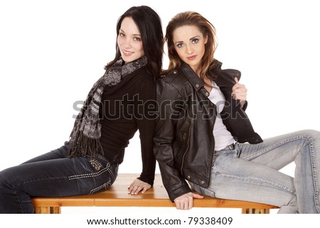 Two women sitting with their backs together looking good.