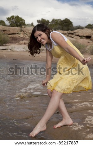 A woman tip toe into the water with a uncertain look on her face.