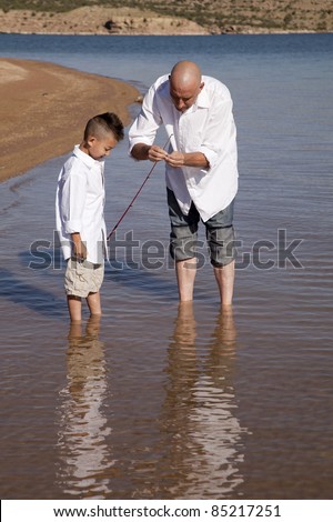 A father fixing his sons pole so he can fish.