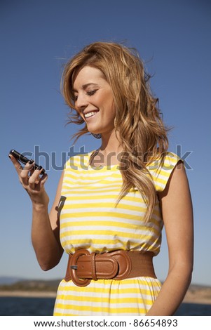 A woman looking down at her phone reading a text laughing.