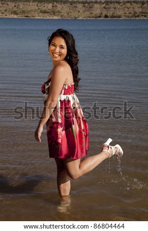 a woman standing in the water with her shoes on with her foot up in the air.