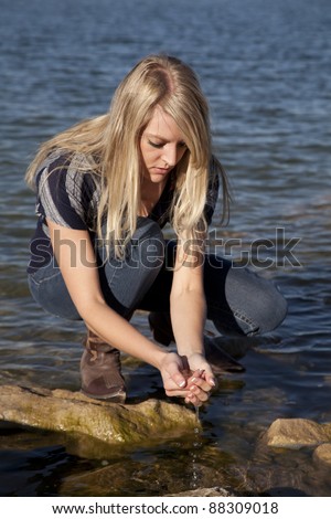 A woman looking down at the water she has in her hands.