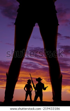 A silhouette of a woman\'s legs up close, watching a man and woman.