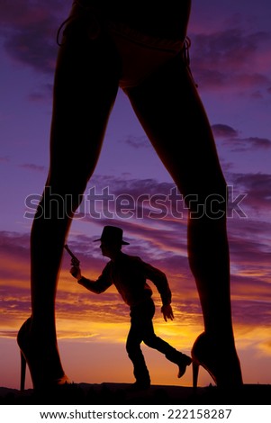 a silhouette of a woman\'s legs with a cowboy with a pistol in between them.