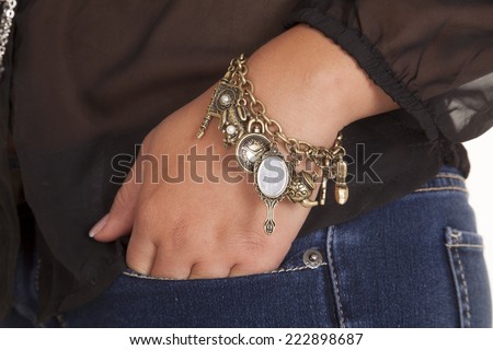a woman with her hand in her pocket with bracelet charms on her wrist.