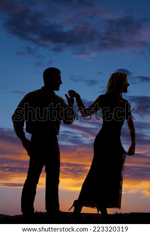 A silhouette of a man holding on to a woman\'s hand.