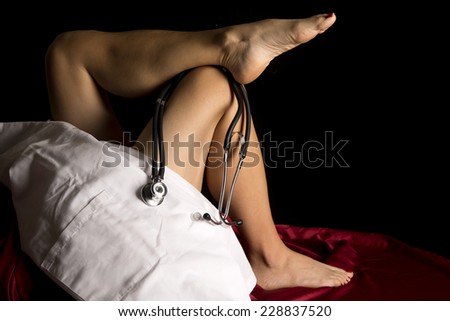 a woman in her bed with her legs up and a doctors jacket and stethoscope.