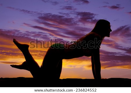 A silhouette of a woman kneeling on the ground looking to the side.