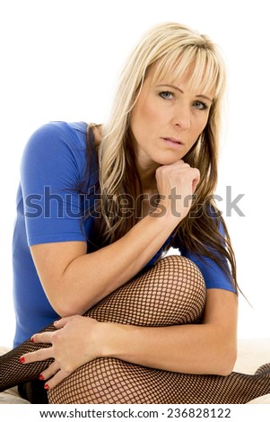 A woman with a serious expression on her face with her legs curled up under her.
