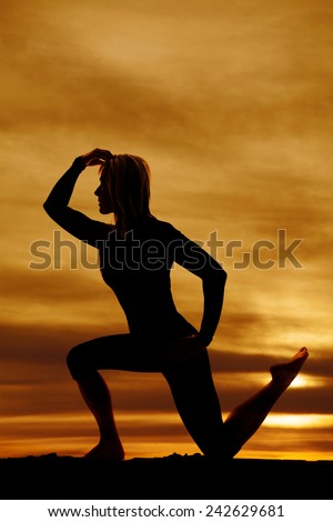 A silhouette of a woman kneeling stretching her body.