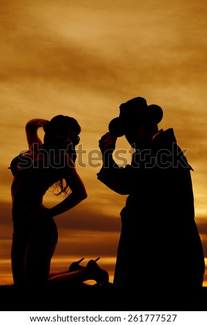 a silhouette of a woman kneeling with her cowboy behind her.