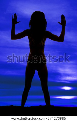 A silhouette of a woman with her hands up.