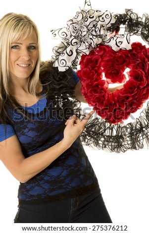 a woman pointing to her heart wreath with a smile.