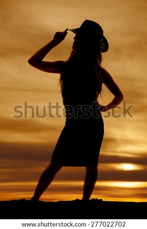 A silhouette of a woman in her dress with her western hat.
