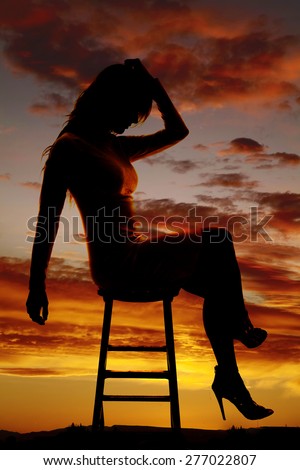 A silhouette of a woman sitting on a stool, with her head down in sadness.