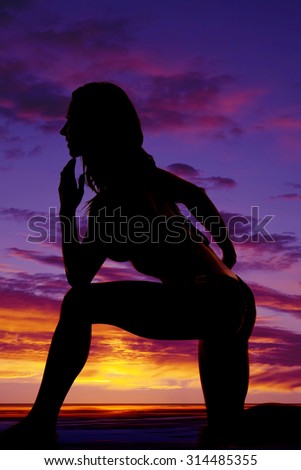 A silhouette of a woman kneeling in her bikini.