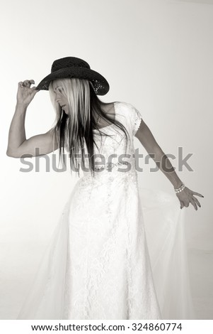 a bride holding on to her cowboy hat looking down to the side.