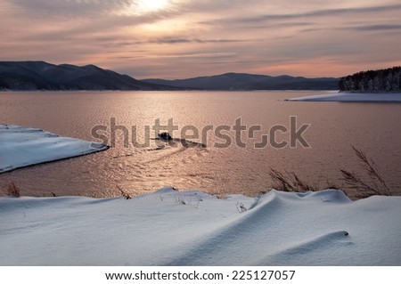 Boat sailing on the lake in winter at sunset