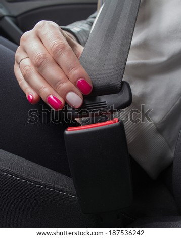 Woman fastening seat belt in car