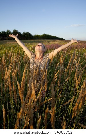 young blonde woman on summer meadow at sunset time