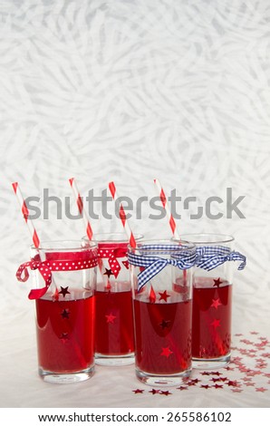 Four festive glasses with red juice, decorative stars and striped straws