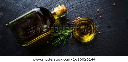 Extra virgin olive oil in a glass bottle, flavored with rosemary and peppercorns on black stone slate ストックフォト © 