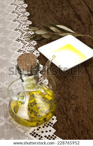 A glass jar with olive oil and olive leaves on old  rustic wooden table background