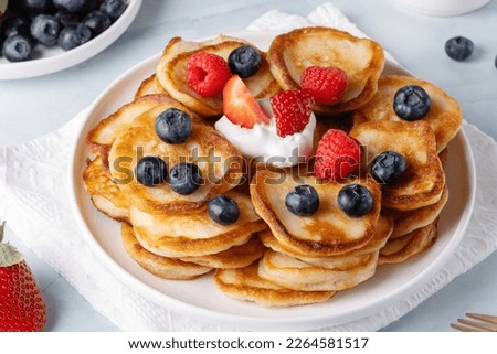 Similar – Image, Stock Photo Mini pancakes with butter and blueberries lie in a plate on a wooden table. Brunch, dessert for children, trending food. Space for text