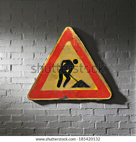 Grunge work in progress road sign on white brick wall man at work