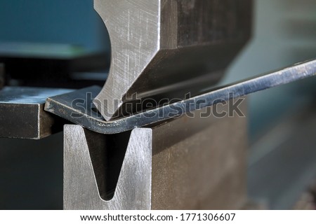 Bending sheet metal with a hydraulic machine at the factory. Closeup. Stockfoto © 