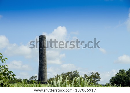 Old sugar cane mill chimney in sugar cane field